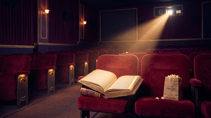 Open book and popcorn on velvet cinema seats beneath a warm projector beam